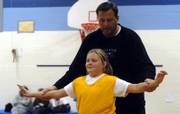Former Kansas University basketball player Mike Maddox shows his daughter, Jamie, 10, how to position herself during her basketball practice Wednesday night at Deerfield School. Ninety-five percent of the coaches in Lawrence’s recreation league are parents, says Lee Ice, youth sports director for Parks and Rec. 